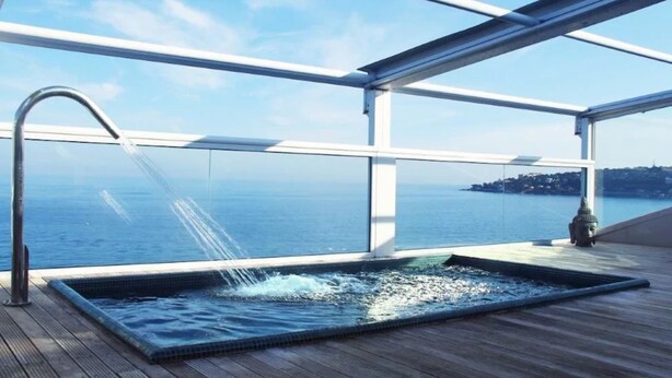 A hot tub on a deck with a view of the sea and a distant island.