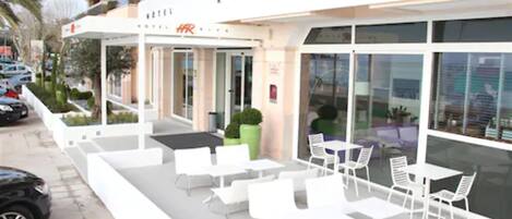 A hotel exterior with outdoor seating and a visible entrance.