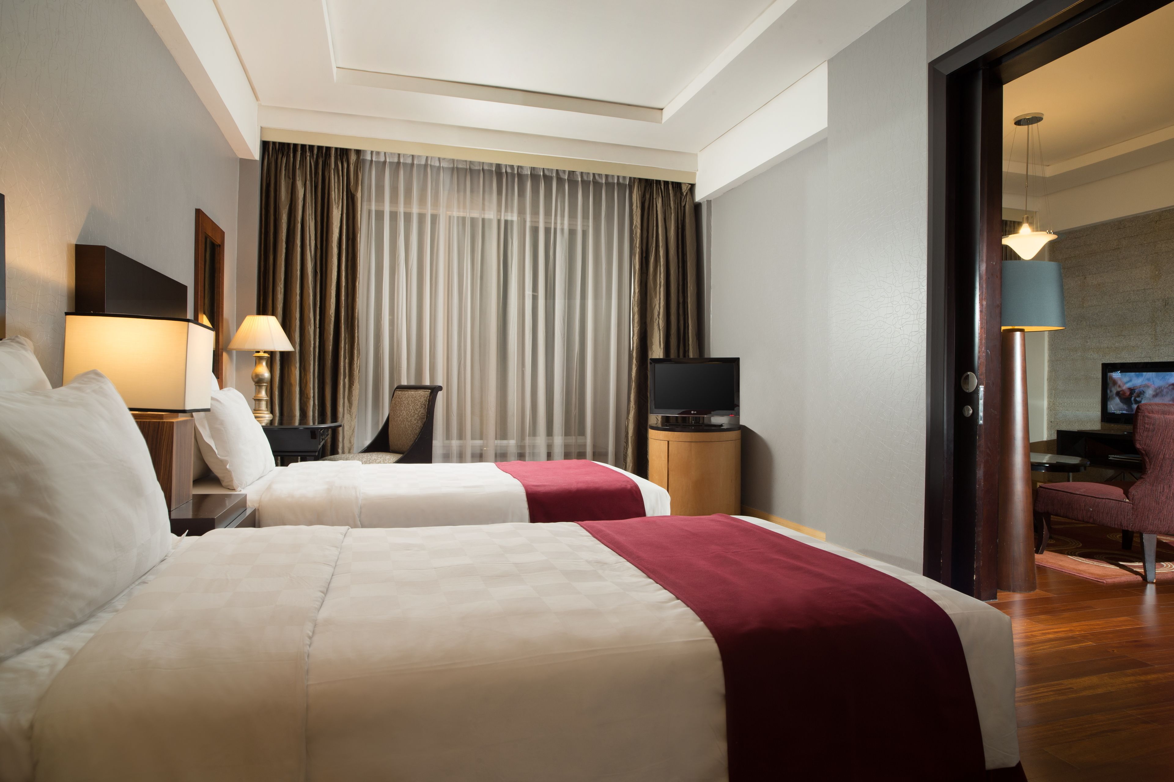 Una habitación de hotel con dos camas, televisión, escritorio y una silla.