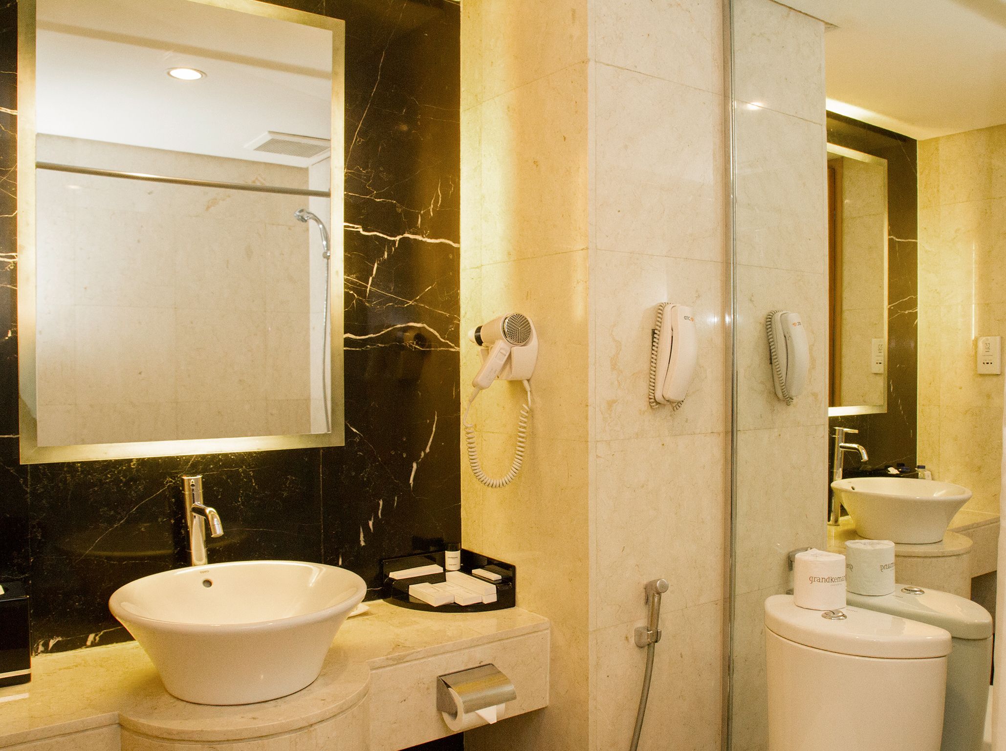 A bathroom with a large mirror, a sink, a toilet, and a shower.