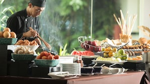 A buffet setup with various food items and a chef preparing food.