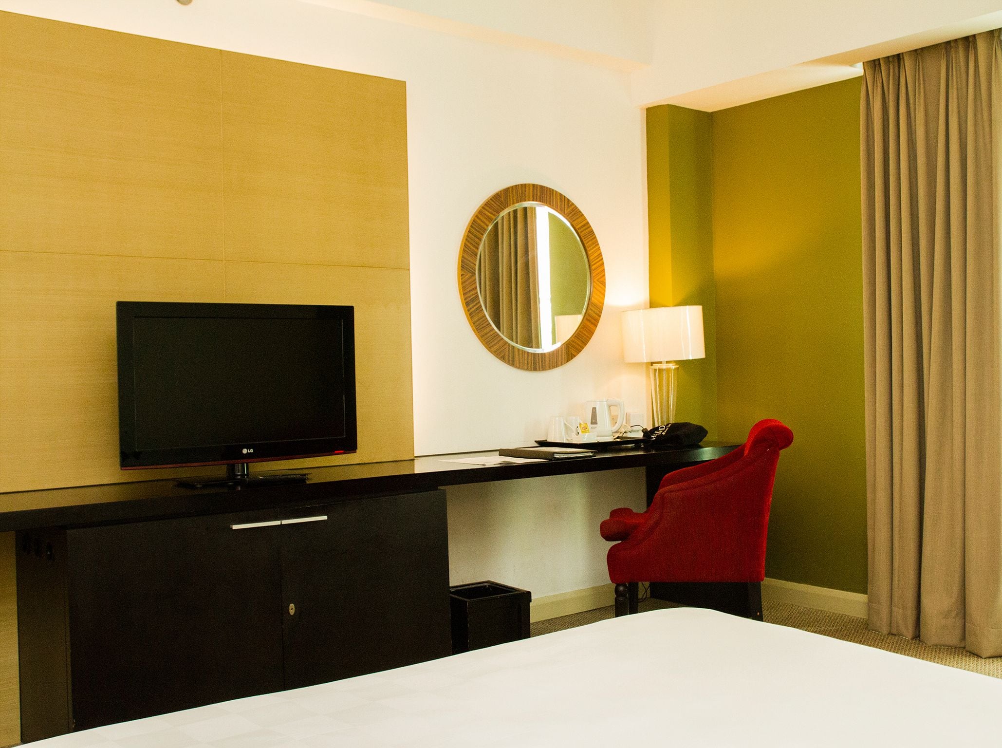 Une chambre d’hôtel équipée d’un lit, d’une télévision, d’un bureau avec une lampe, d’une chaise et d’un miroir.
