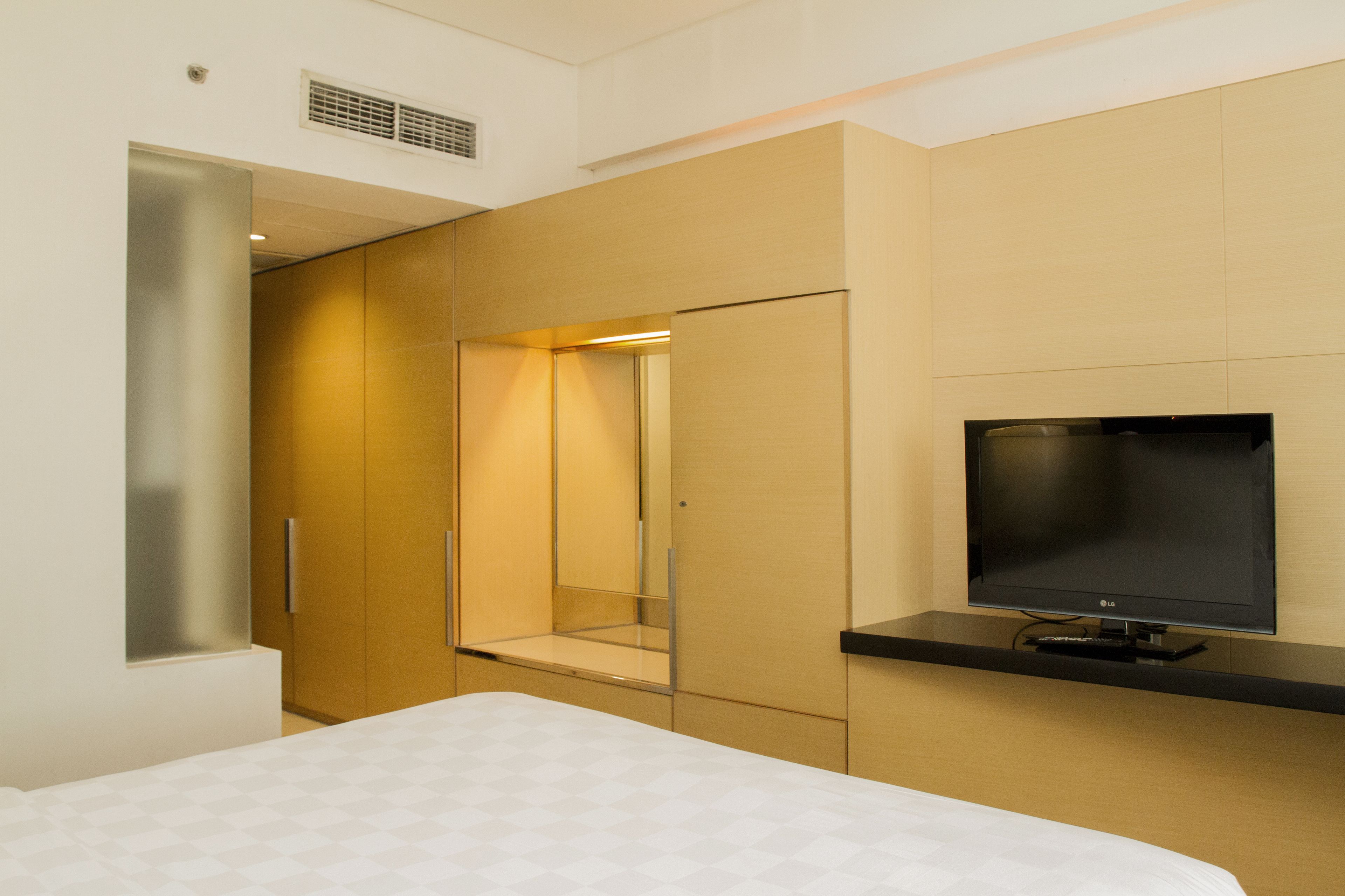 Une chambre d’hôtel moderne équipée d’un lit, d’une télévision et d’une armoire.