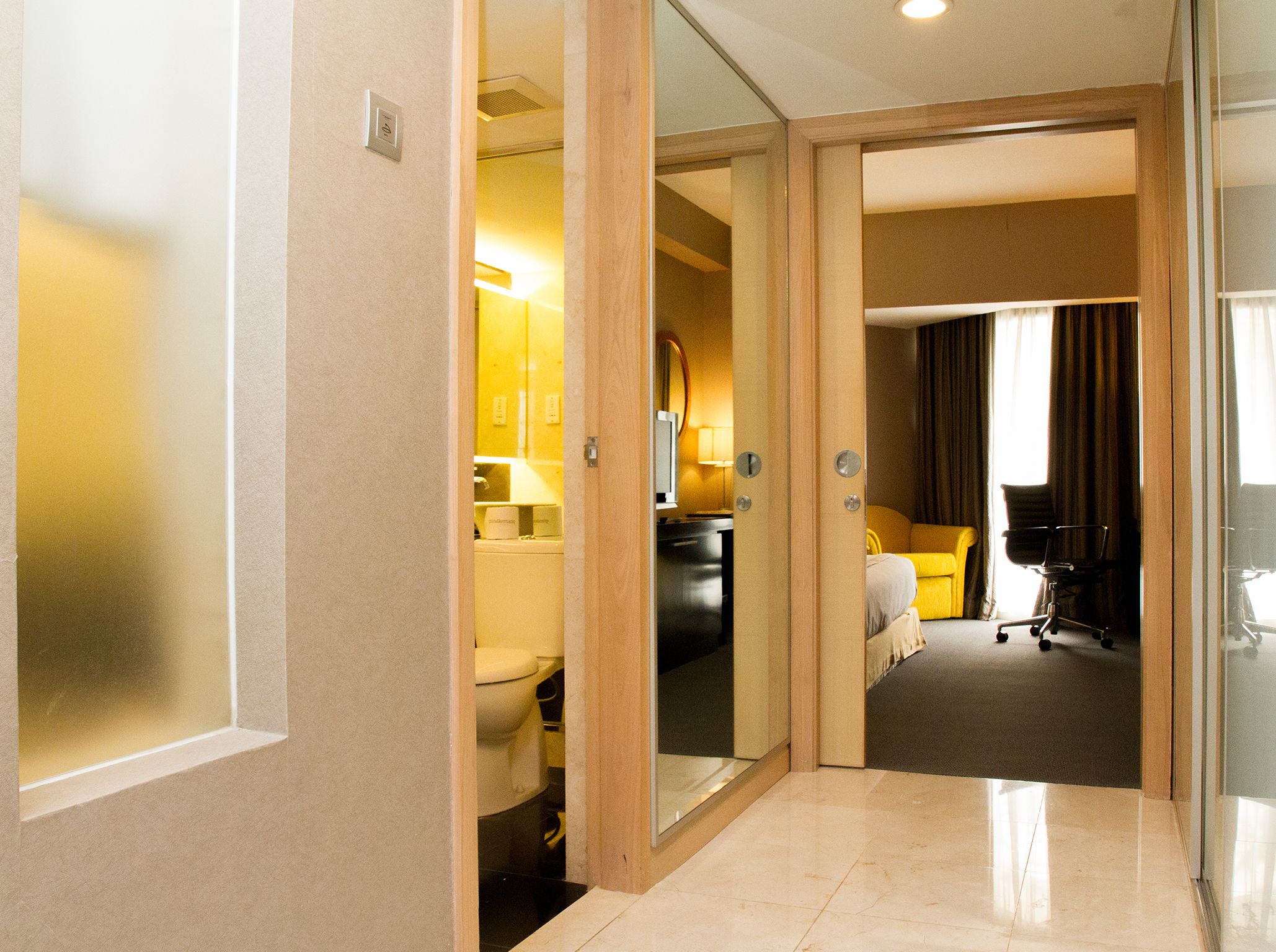 A hotel room with a bathroom, a bed, a desk, and a chair.