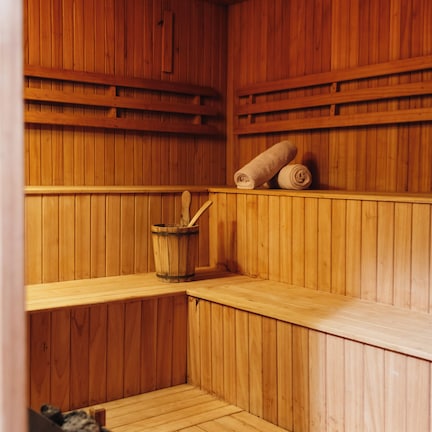 A wooden sauna with benches, a wooden bucket, and towels.