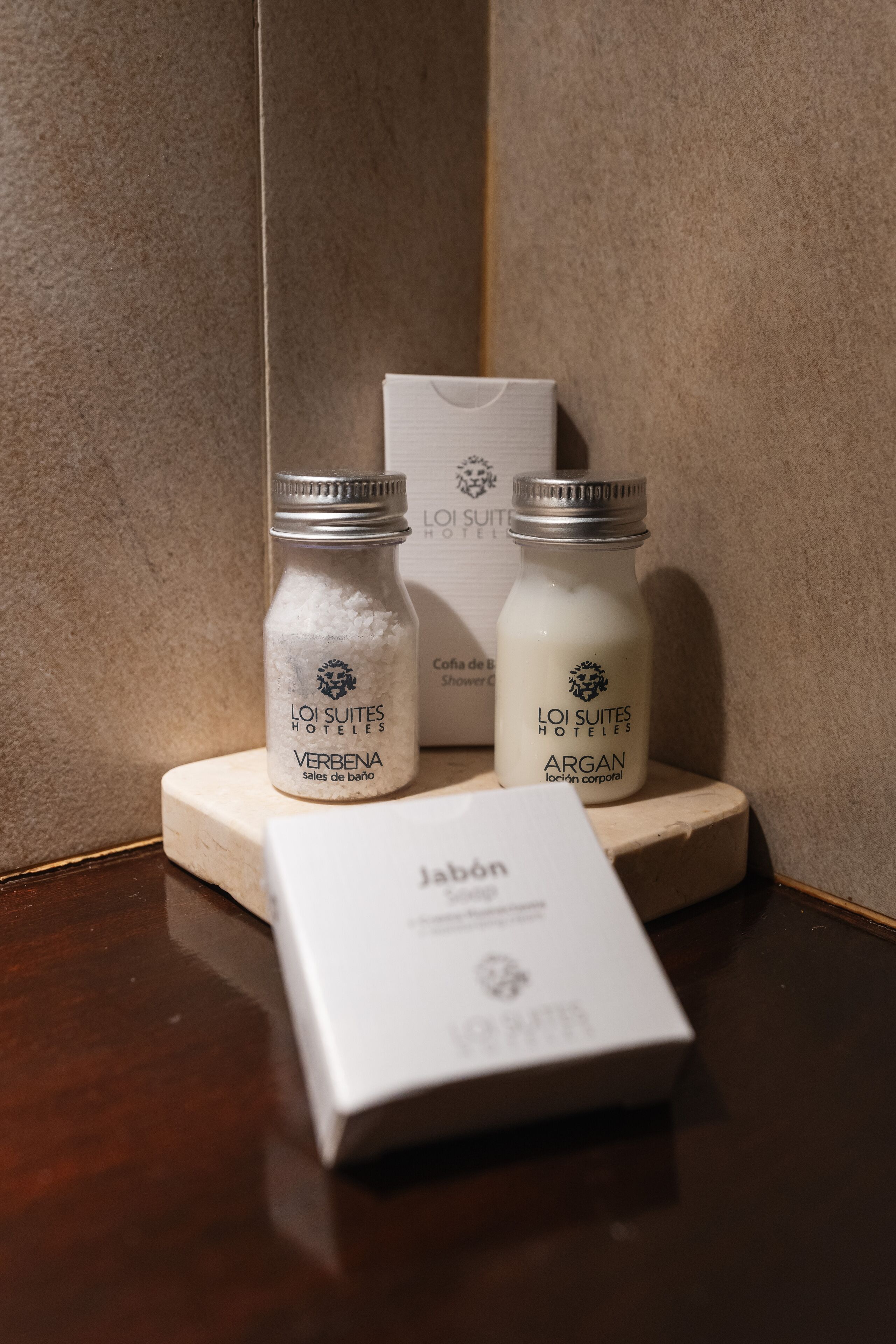 Two bottles of toiletries labeled 'LOI SUITES HOTELS' on a wooden surface with a white box in front.