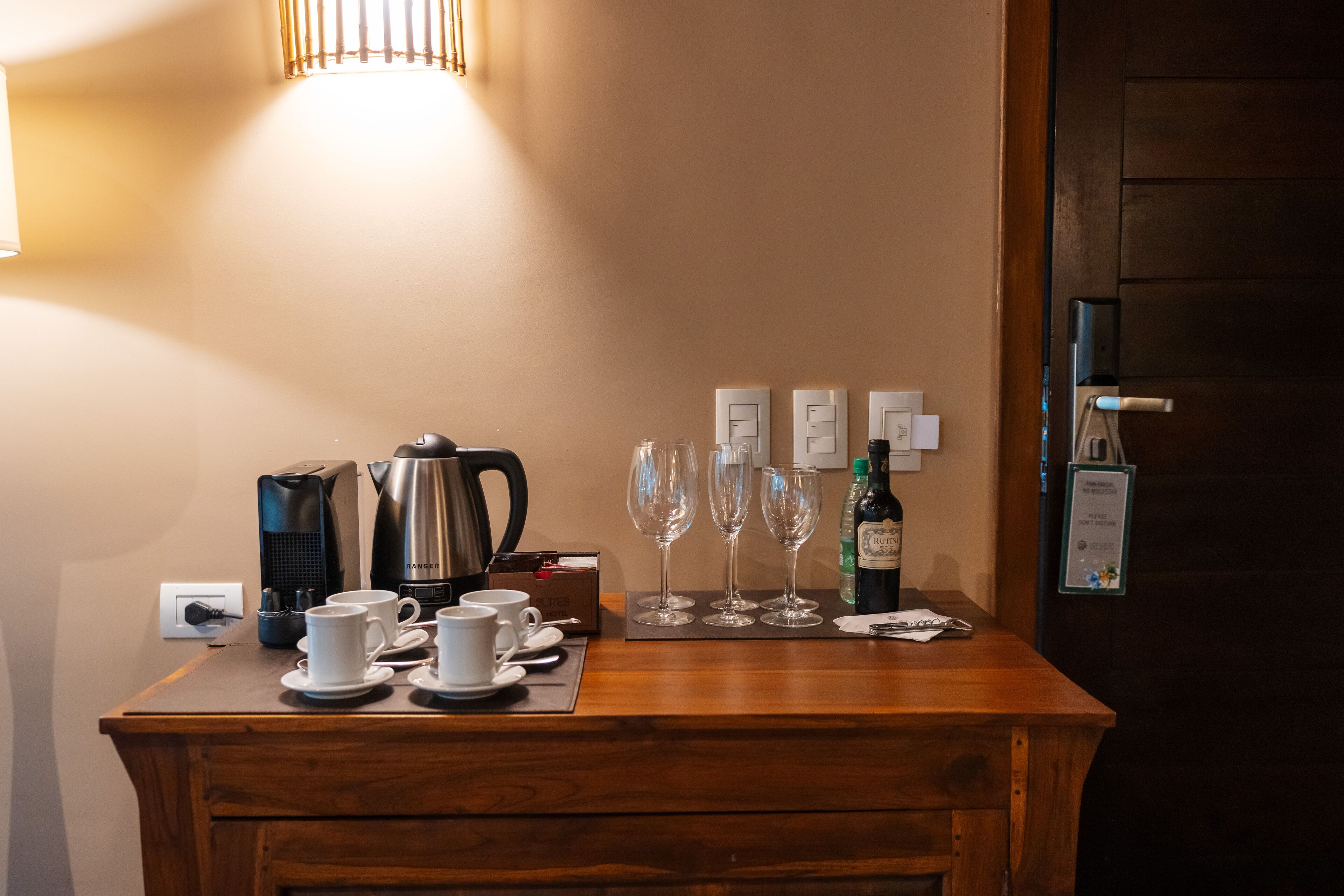A wooden counter with coffee makers, cups, and wine glasses.