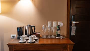 A wooden counter with coffee makers, cups, and wine glasses.
