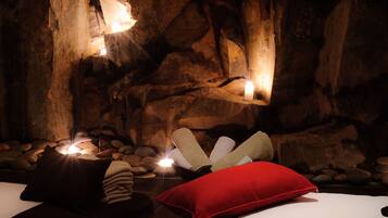 Relax in a serene spa room with a natural rock wall backdrop and a comfortable single bed.