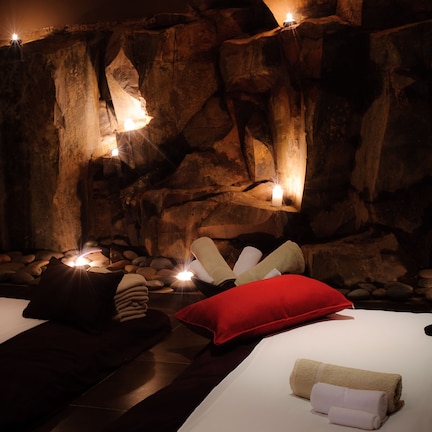 A spa room with a bed, pillows, and a wall with candles.