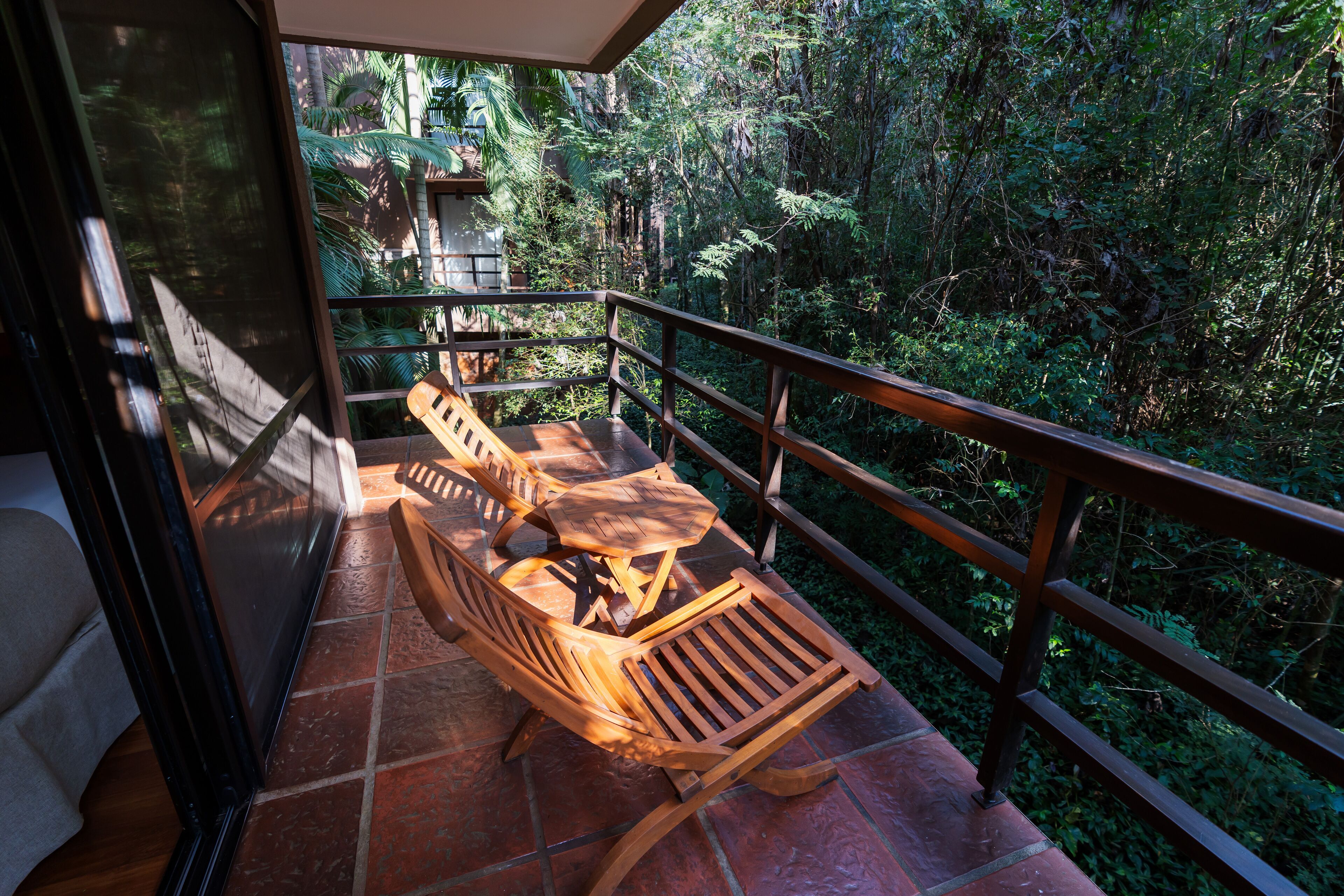 Un balcon doté de mobilier en bois et offrant une vue sur une végétation luxuriante.