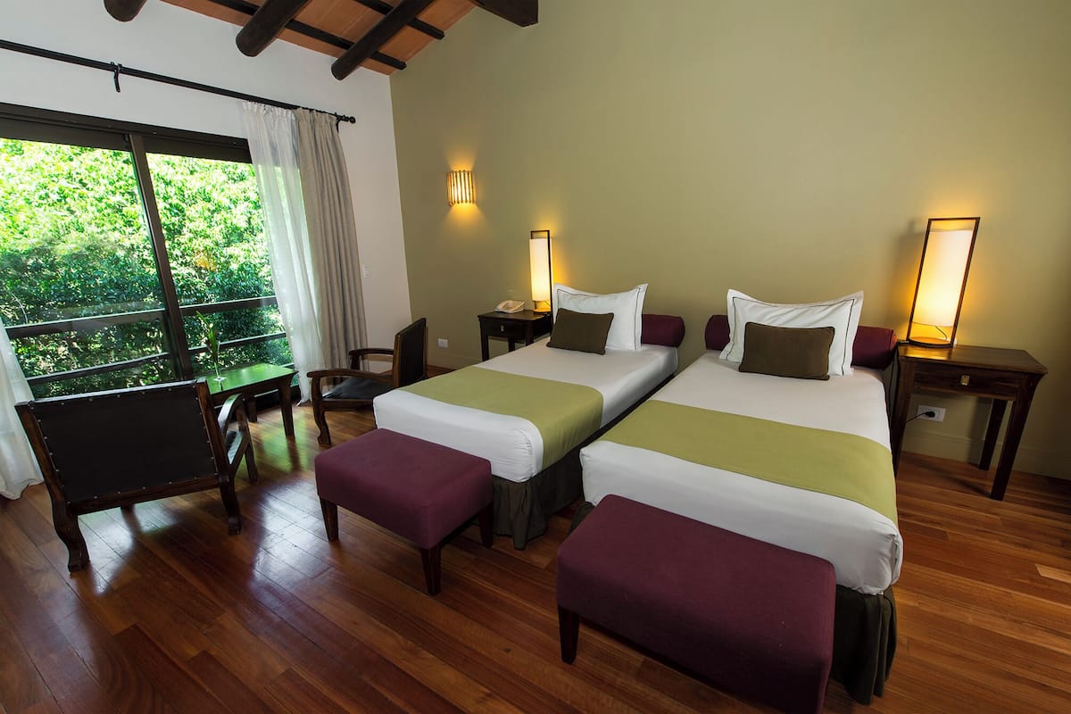A hotel room with two beds, a desk, and a chair.
