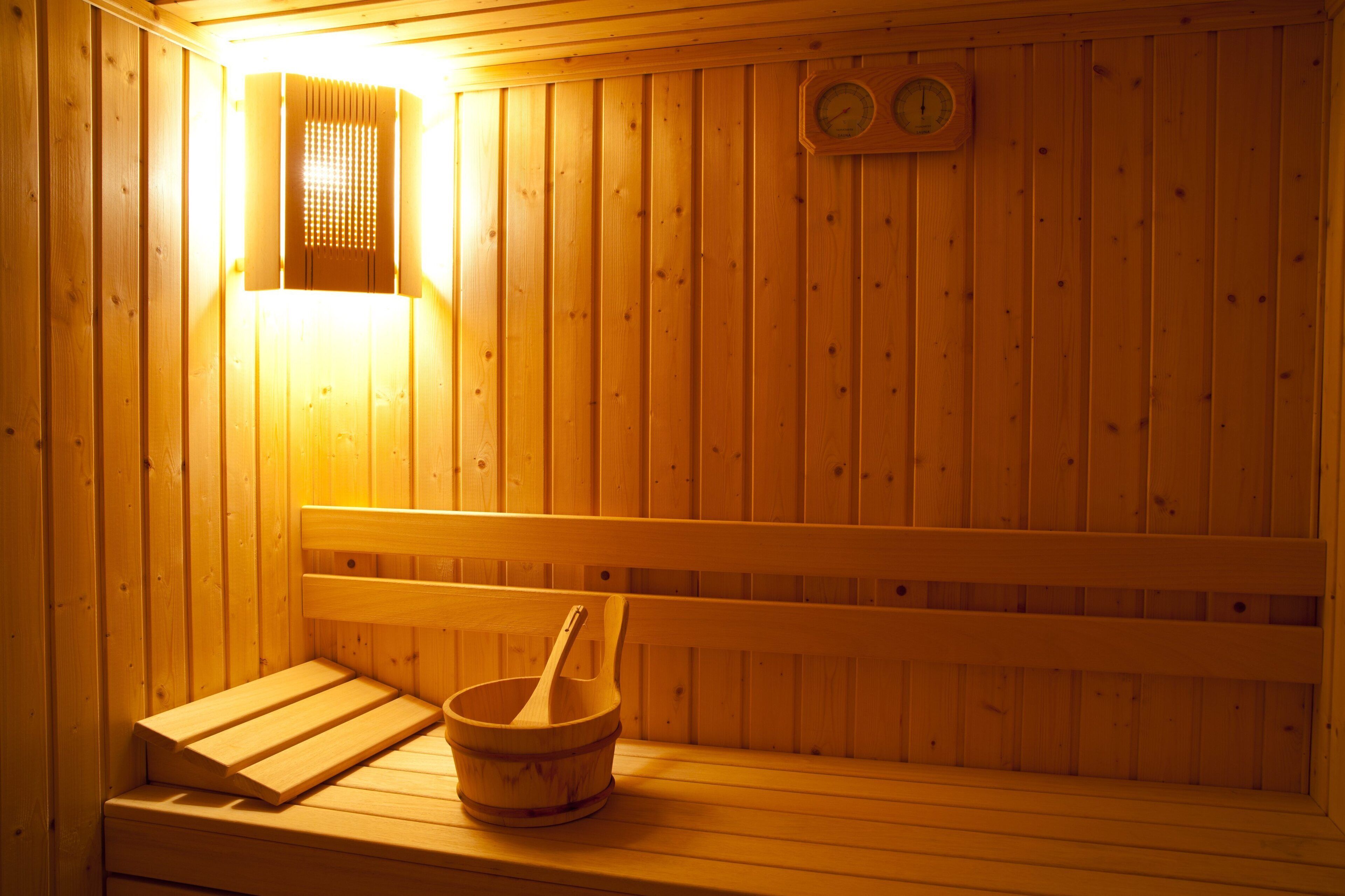 A wooden sauna with benches and a wooden bowl.