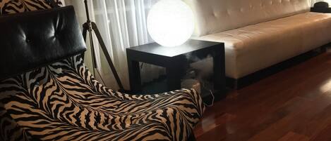 A modern living room with a zebra-patterned chair, a black side table with a spherical lamp, and a white sofa.