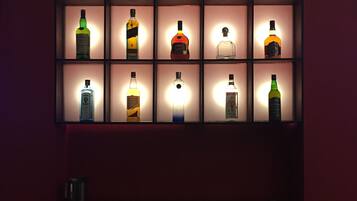 Paredes com prateleiras iluminadas exibindo diversas garrafas de bebidas alcoólicas.