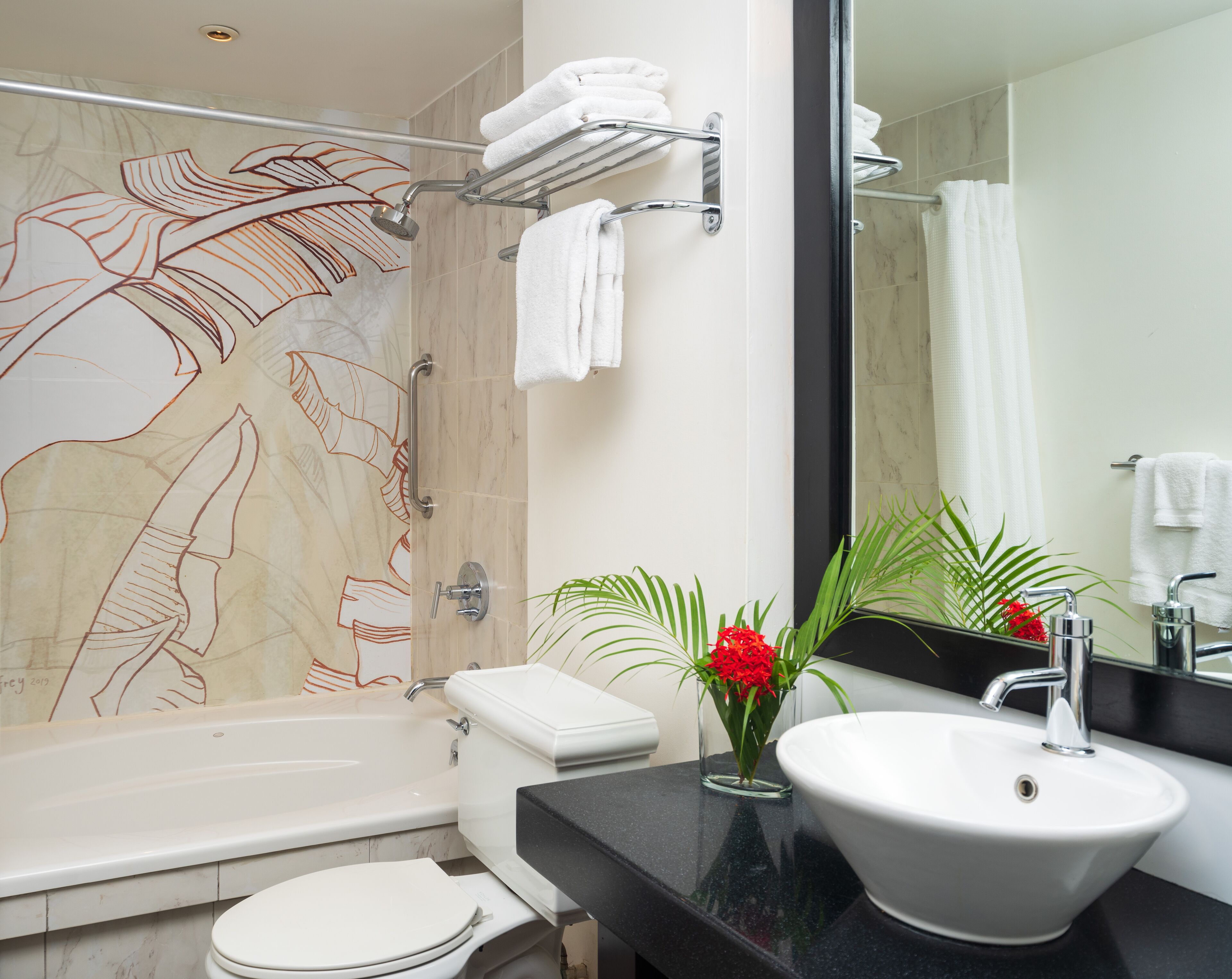 A modern bathroom with a bathtub, toilet, sink, and a large mirror.