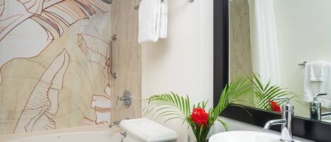 A modern bathroom with a bathtub, toilet, sink, and a large mirror.