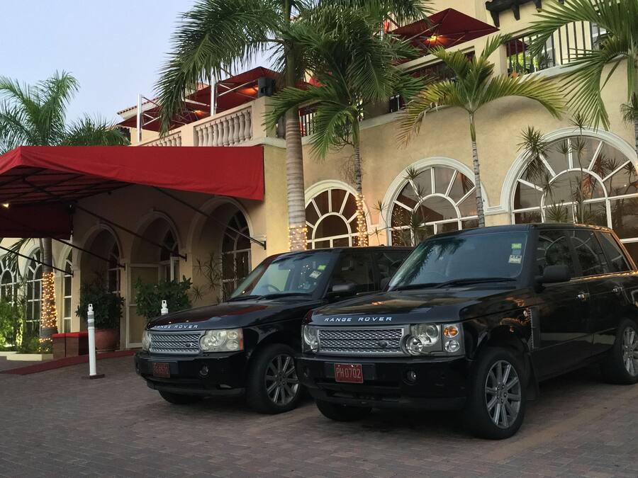 Two black Range Rover SUVs parked in front of a building with arched windows and a red awning.