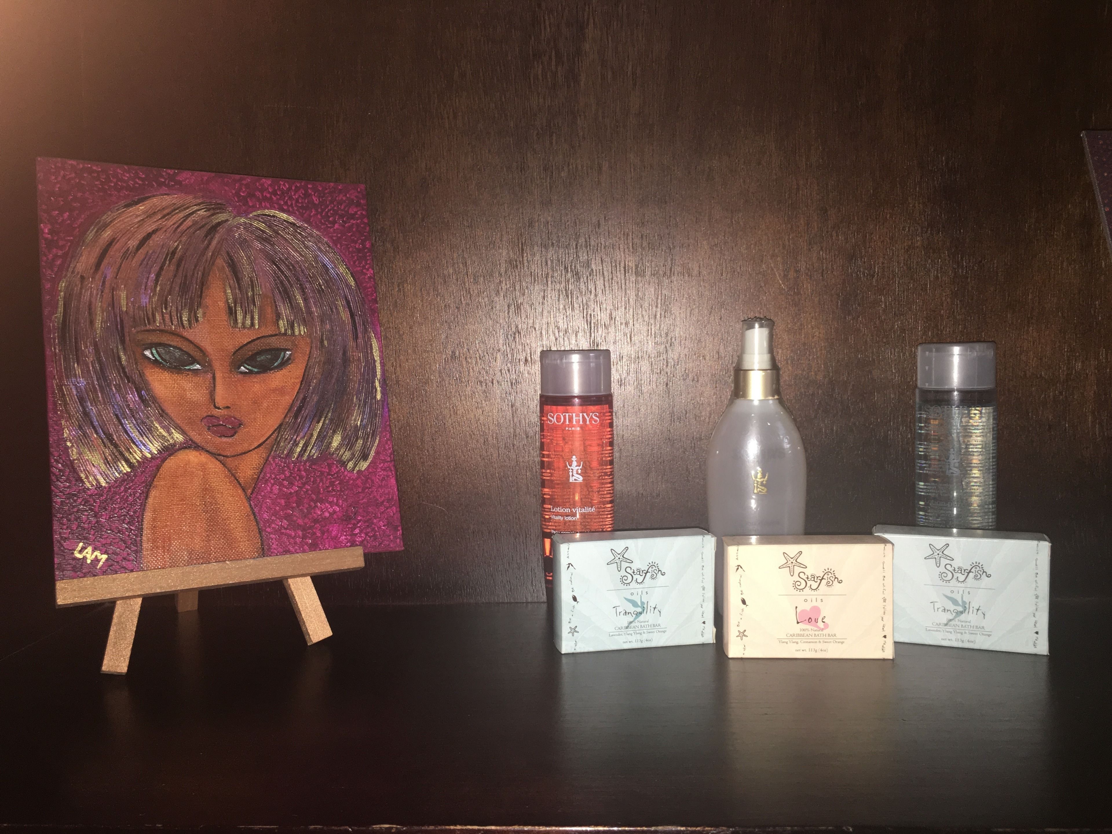 Uma pintura em um cavalete, três frascos de produtos para a pele e três caixas de produtos de banho.