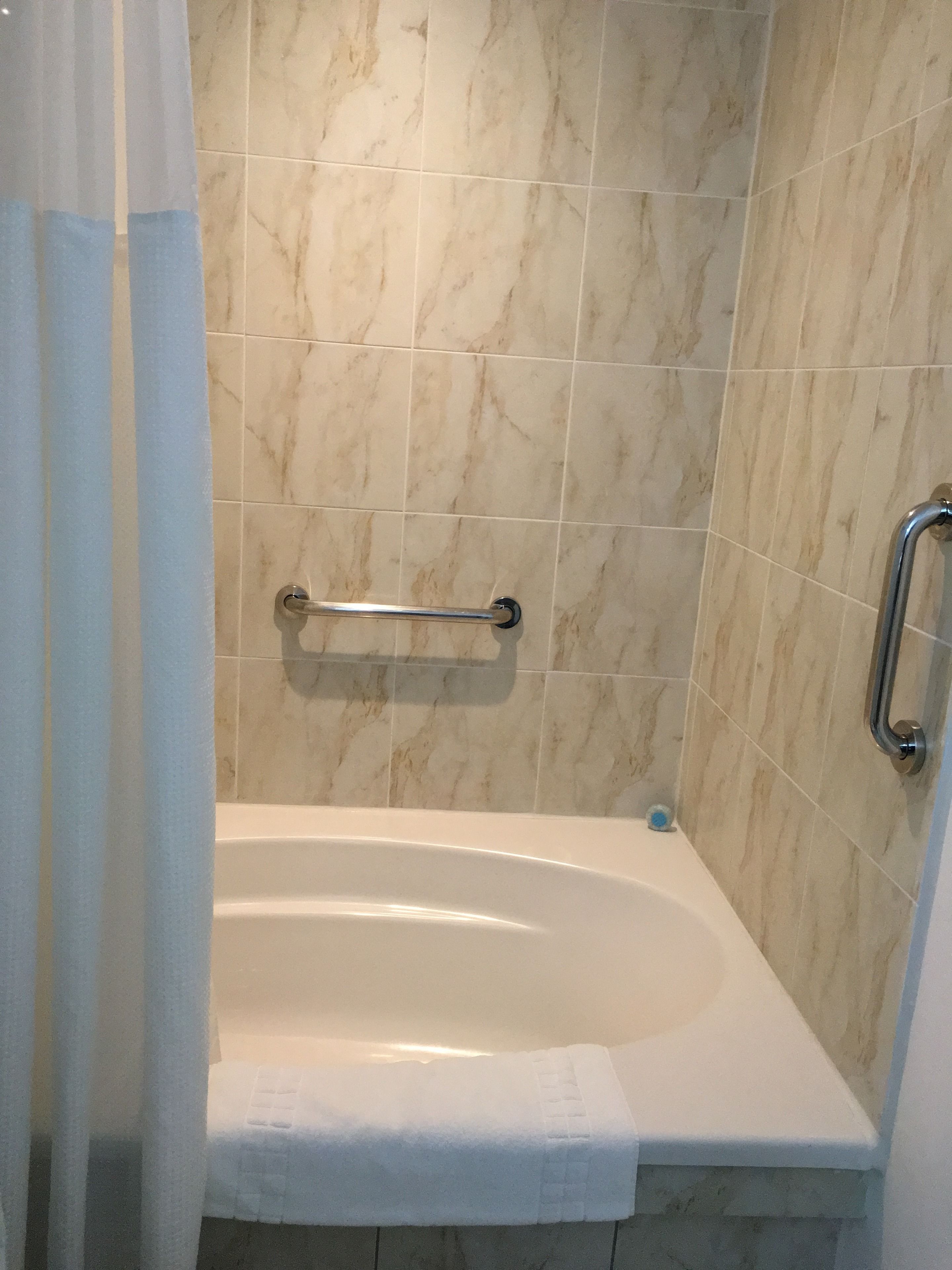 Ein Badezimmer mit Badewanne, Haltegriff und Handtuchhalter.
