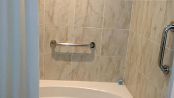 Une salle de bain équipée d’une baignoire, d’une barre d’appui et d’un porte-serviettes.