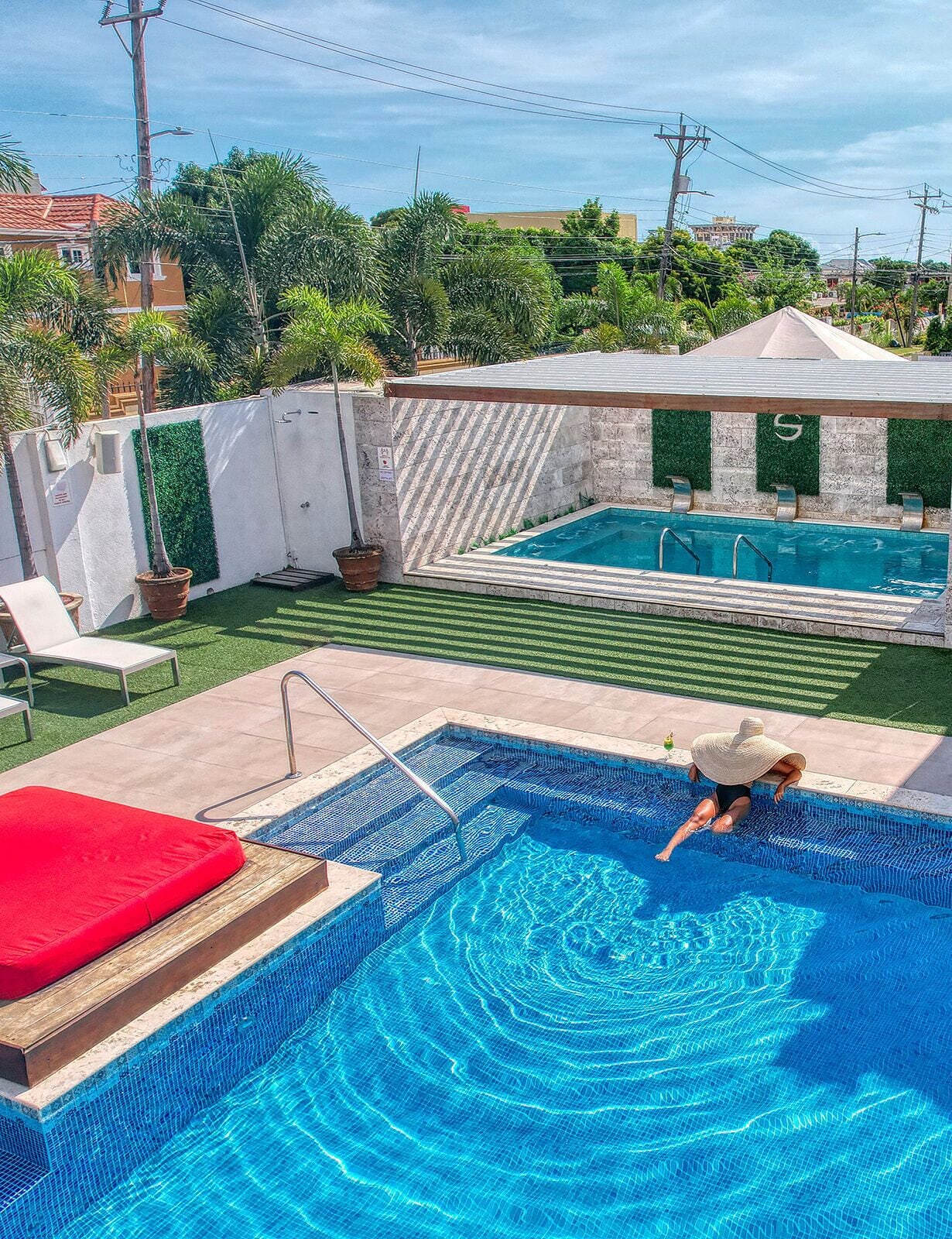 A swimming pool with a diving board, a red lounge chair, and a small deck area.