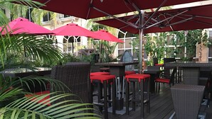 An outdoor patio area with wicker furniture, red cushions, and red umbrellas. - S Hotel Kingston (Kingston)