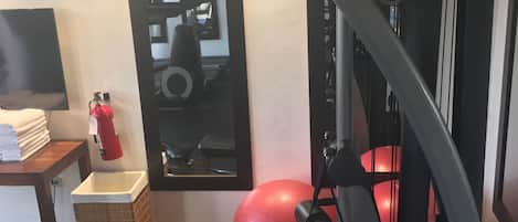 A gym with a treadmill, exercise balls, and a mirror.