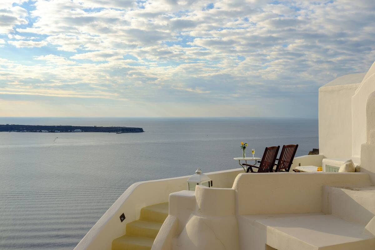 Um terraço à beira-mar com vista para o mar e uma ilha distante.