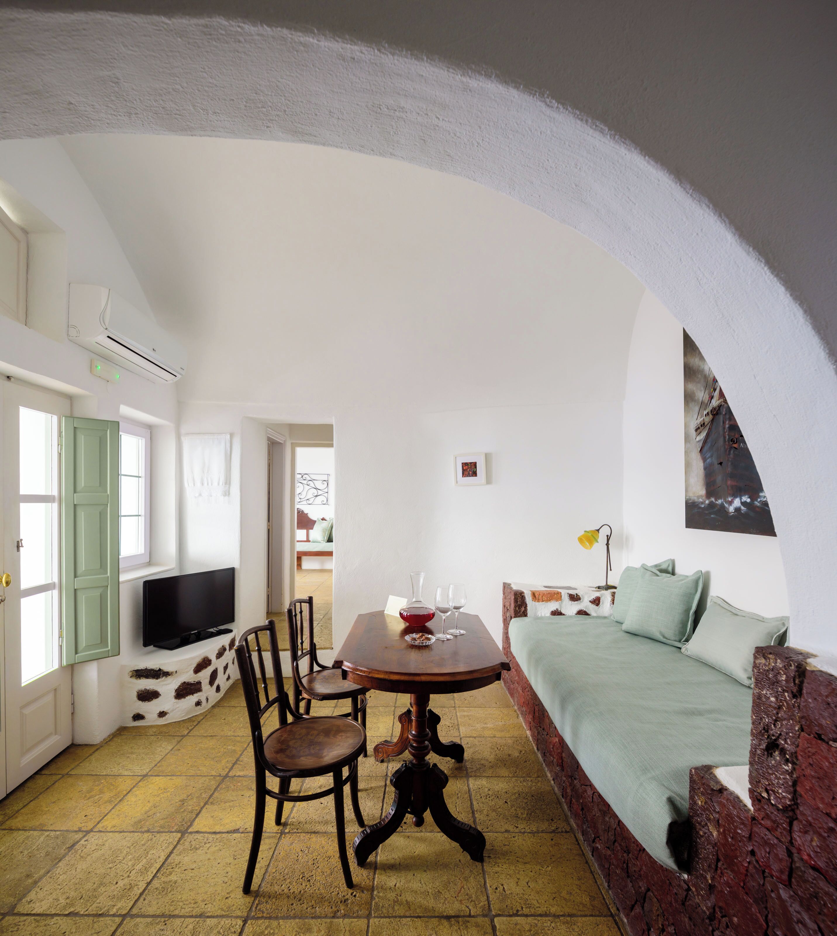 A cozy living room with a wooden table, chairs, a sofa, and a television.