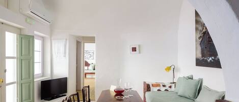 A cozy living room with a wooden table, chairs, a sofa, and a television.