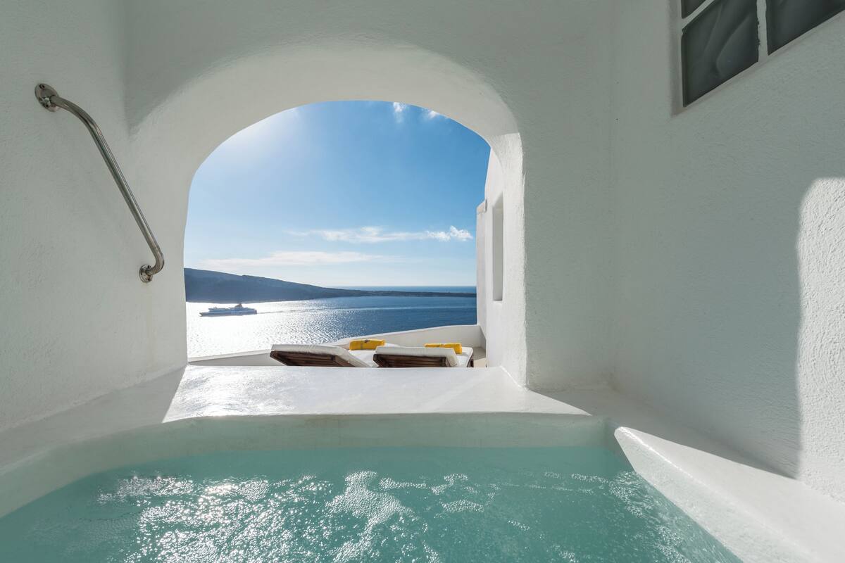 Uma banheira com vista para o mar e um navio ao longe.