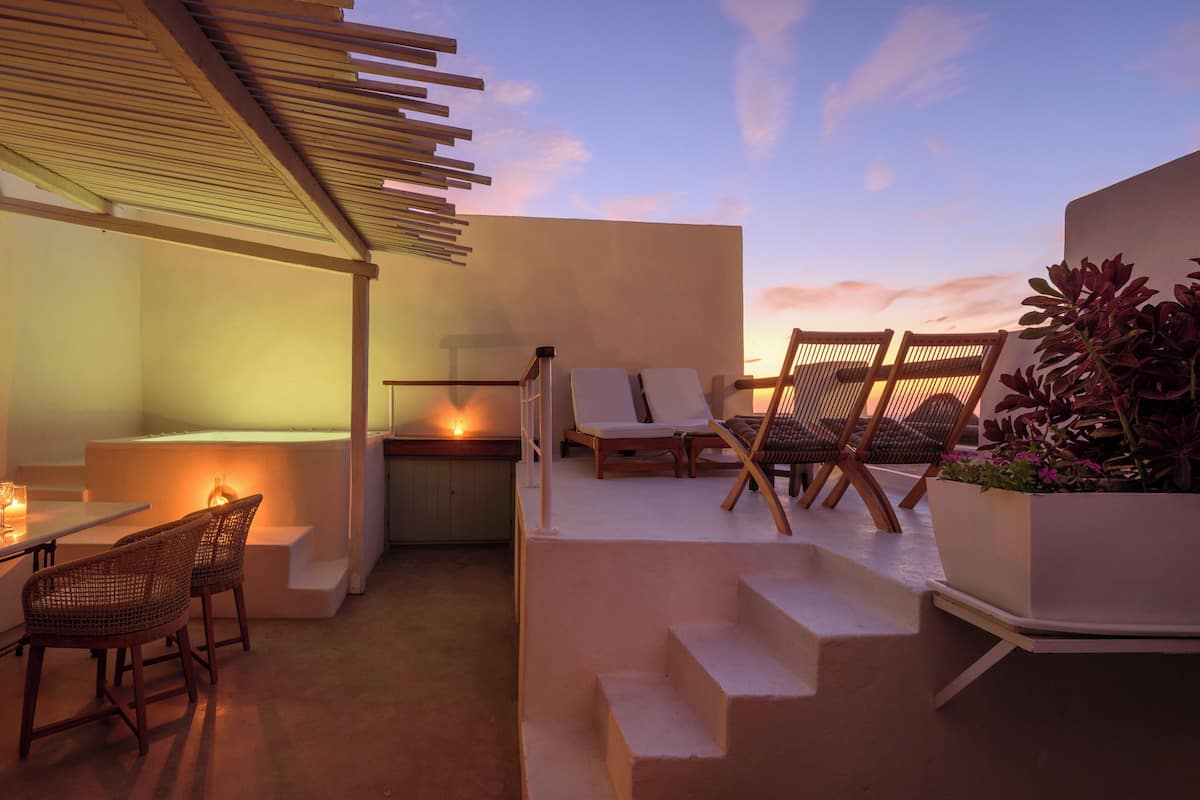 Terraço no telhado com área de estar, uma mesa pequena e um espaço para fogueira.