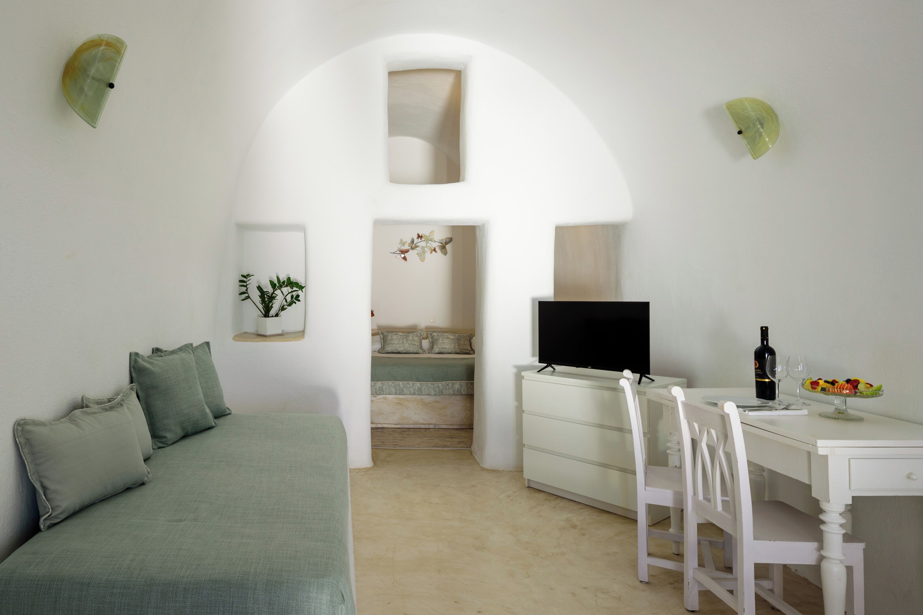 A minimalist bedroom with a bed, a desk, and a television.