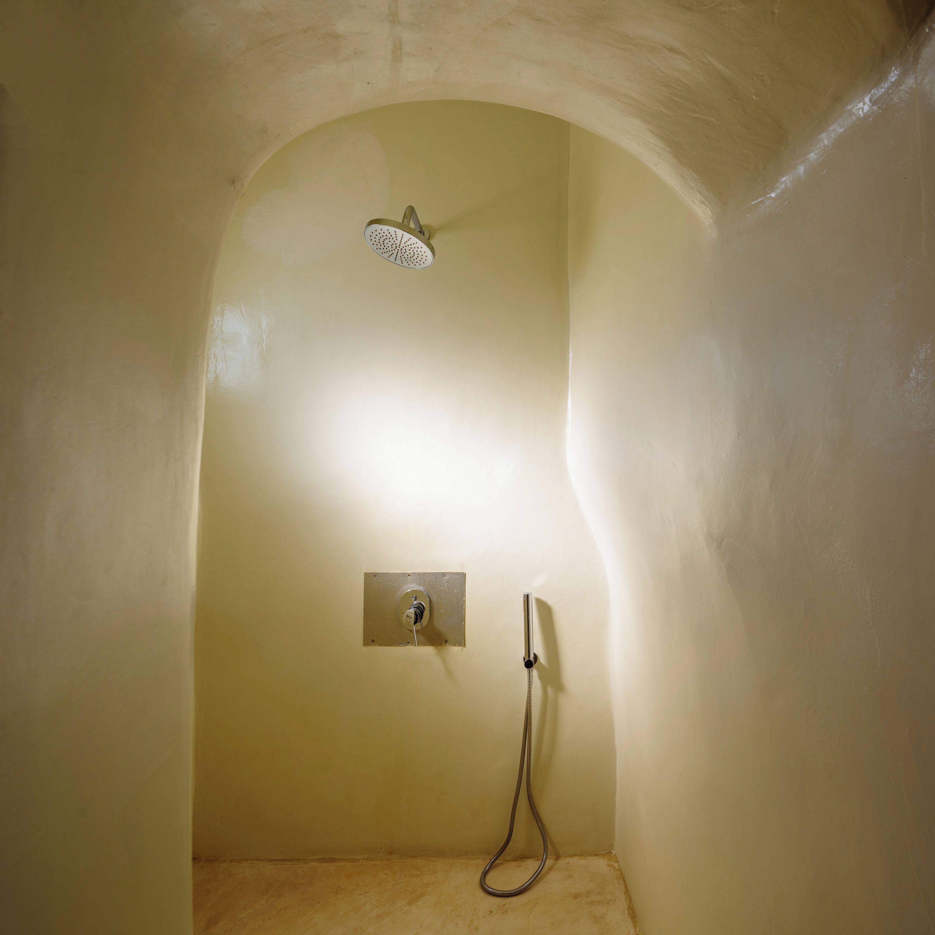 A shower with a handheld showerhead and a wall-mounted control panel.