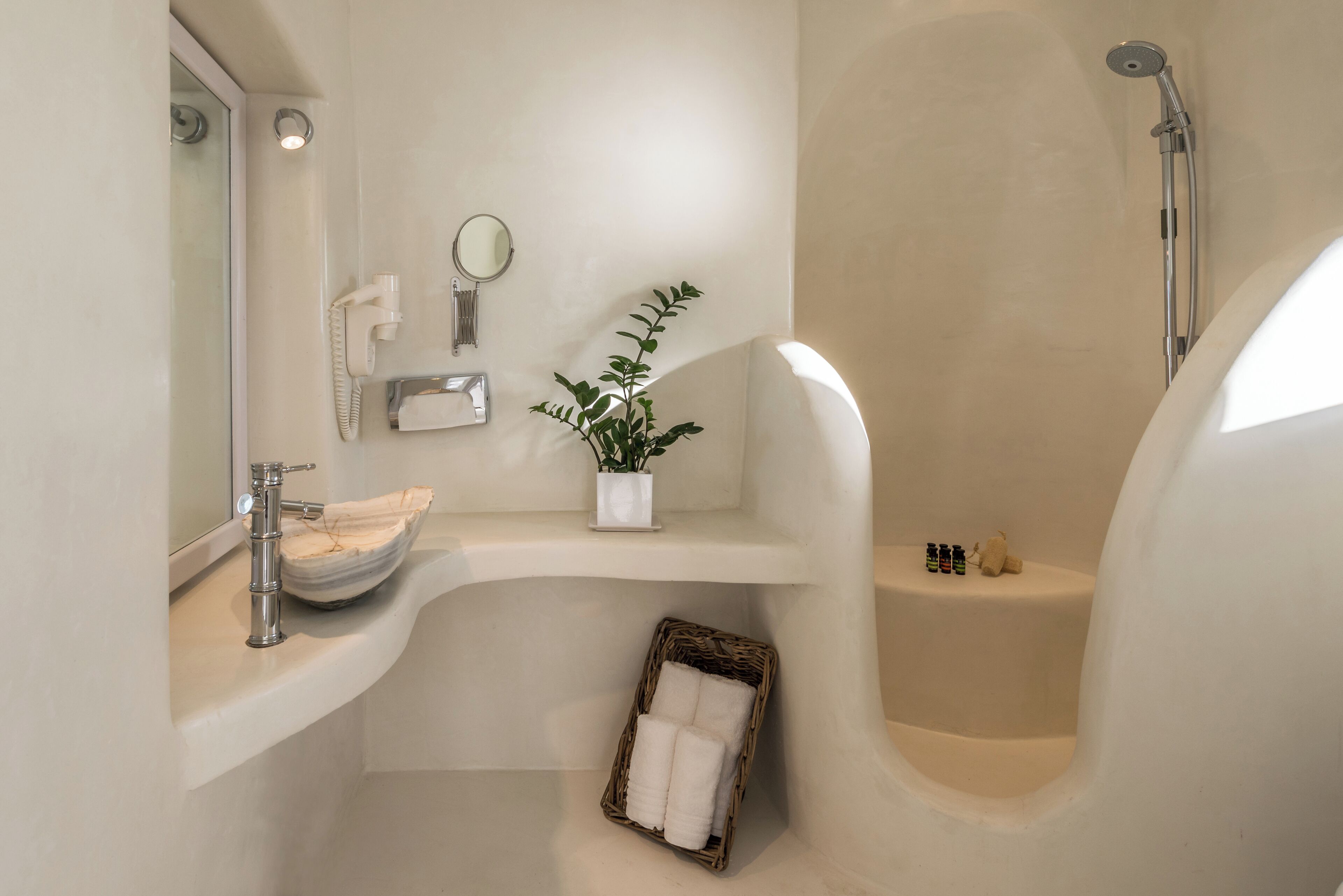 Une salle de bain moderne avec une baignoire sur pieds, un meuble-lavabo avec un miroir, une plante et un panier en osier contenant des serviettes.