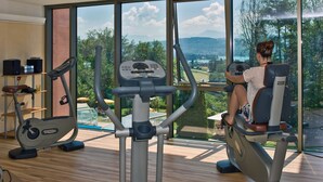 Une salle de sport dotée d’une grande fenêtre offrant une vue panoramique sur les montagnes et les arbres.