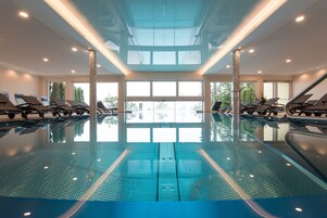 Una piscina techada, una piscina al aire libre, sombrillas