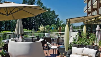 An outdoor patio with seating, umbrellas, and a view of the surrounding greenery.