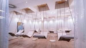 Un espace de spa moderne doté de plusieurs fauteuils de massage, de panneaux de plafond en bois et d’un design minimaliste.