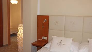 A hotel room with a bed, a nightstand, a lamp, and a shower area.