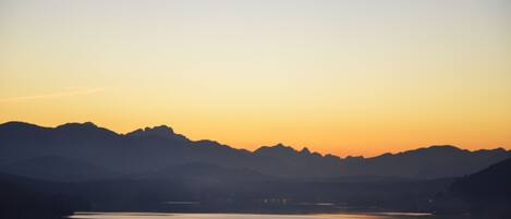 Una vista panorámica de un lago al atardecer con montañas al fondo.
