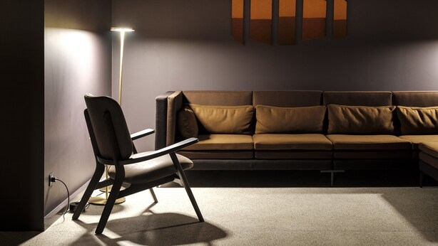 A modern living room with a brown sofa, a black chair, and a floor lamp. - Pousada de Manteigas, São Lourenço (Manteigas)