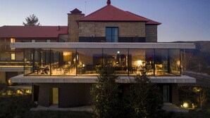 A modern house with a glass-enclosed dining area, stone walls, and a red-tiled roof. - Pousada de Manteigas, São Lourenço (Manteigas)