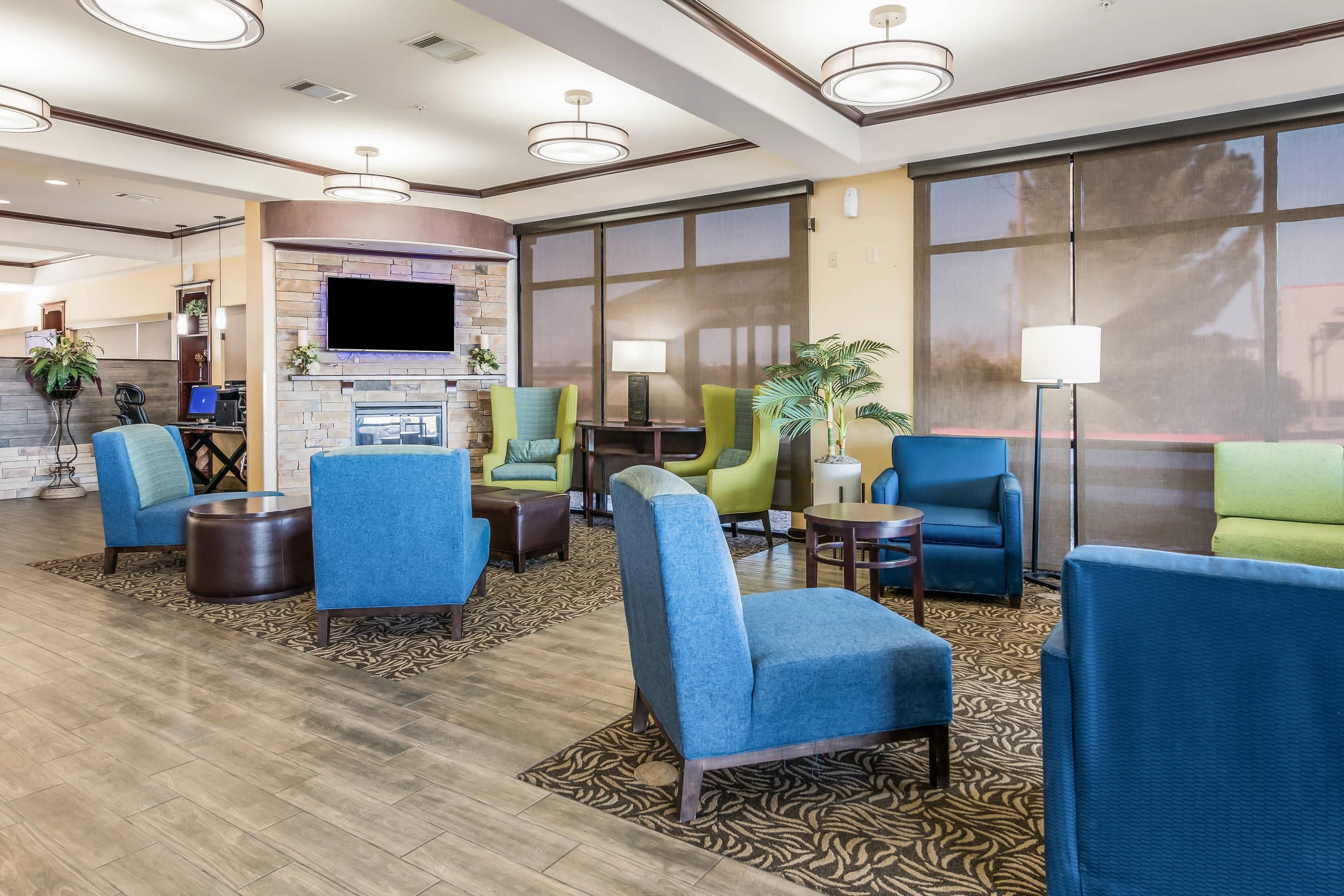 A hotel lobby with a fireplace, seating area, and large windows.
