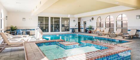 Una piscina interior con sillas de descanso y zona de hidromasaje.