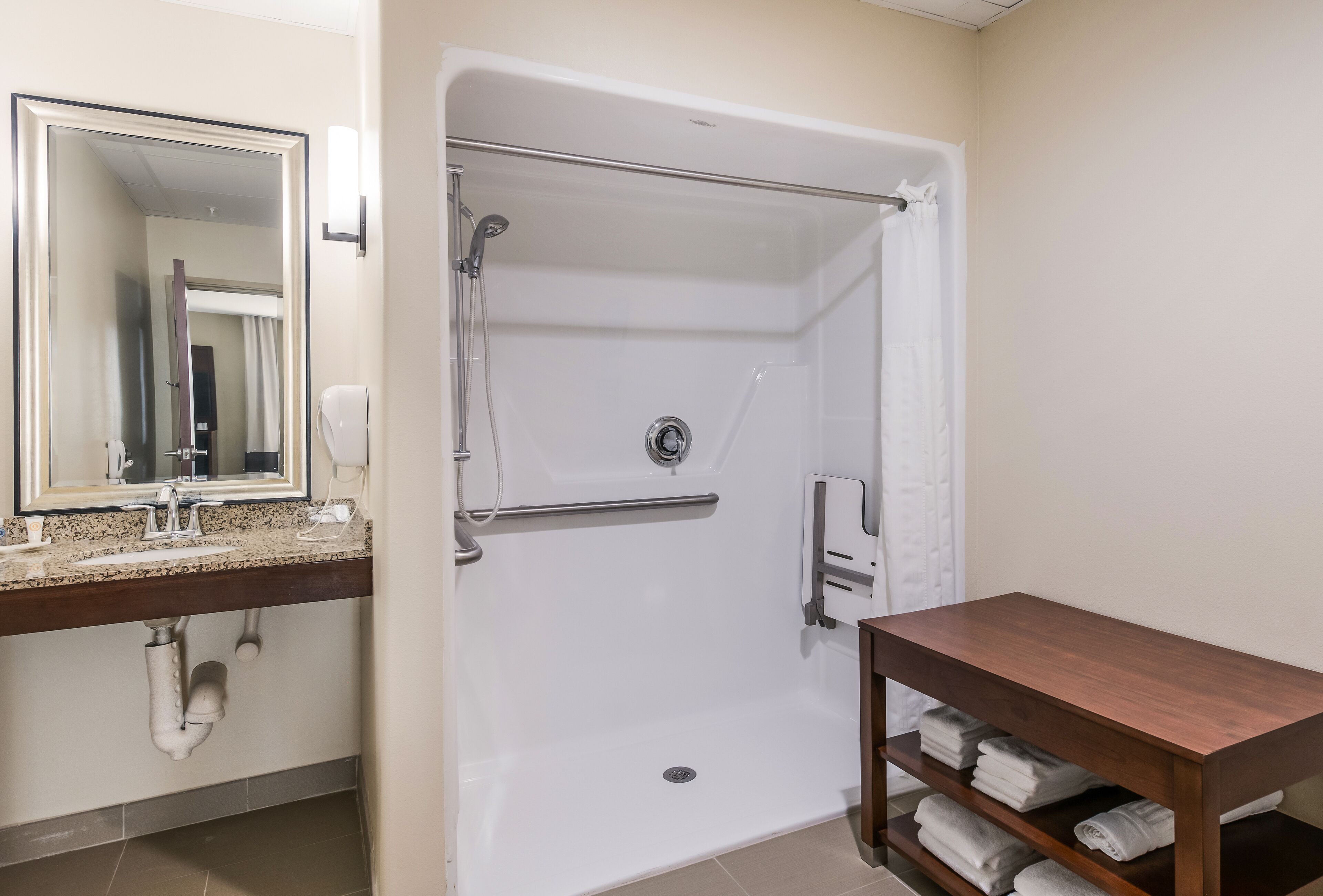 Une salle de bain avec une baignoire, un lavabo avec un miroir et une étagère avec des serviettes.