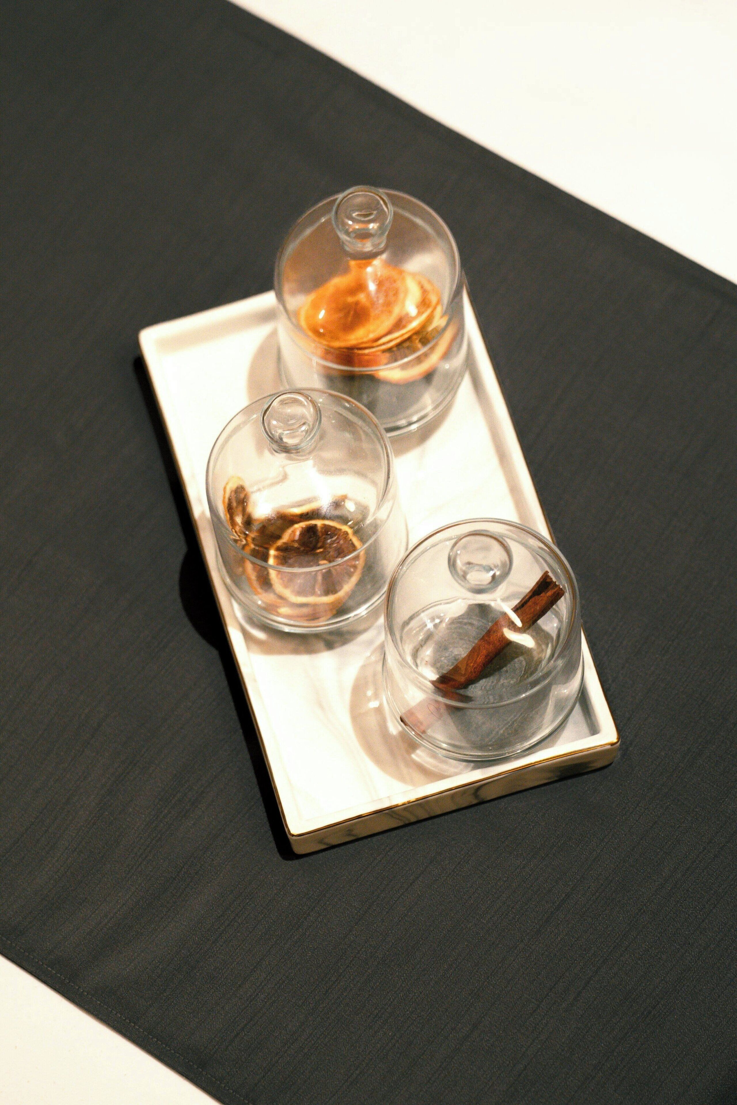 A tray with three glass containers, each containing a different liquid and a cinnamon stick.