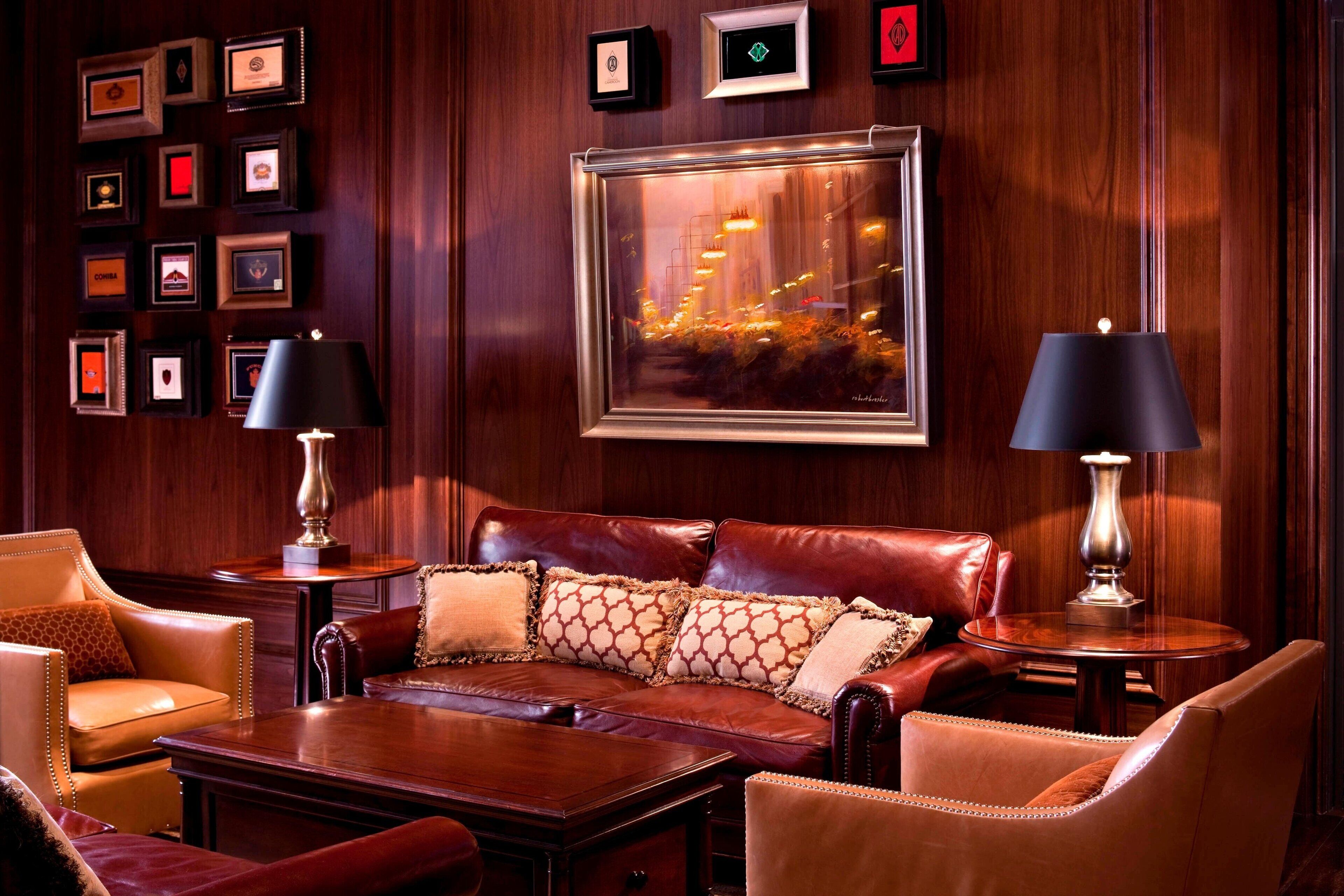 A luxurious room with a leather sofa, two side tables with lamps, a coffee table, and framed pictures on the wall.
