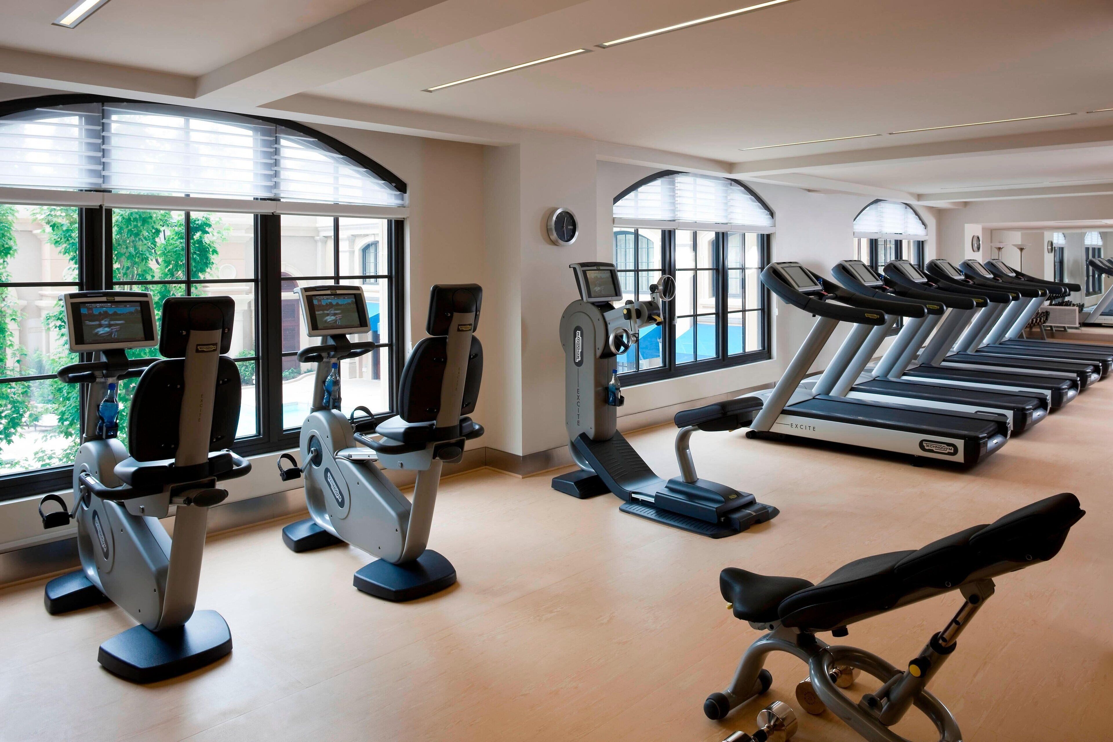 A gym with cardio machines, a rowing machine, and a bench.